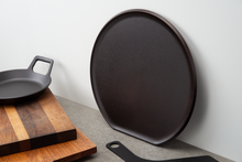 Load image into Gallery viewer, The distinctive flat edge on this heavy pizza griddle prevents it from rolling when stored upright.
